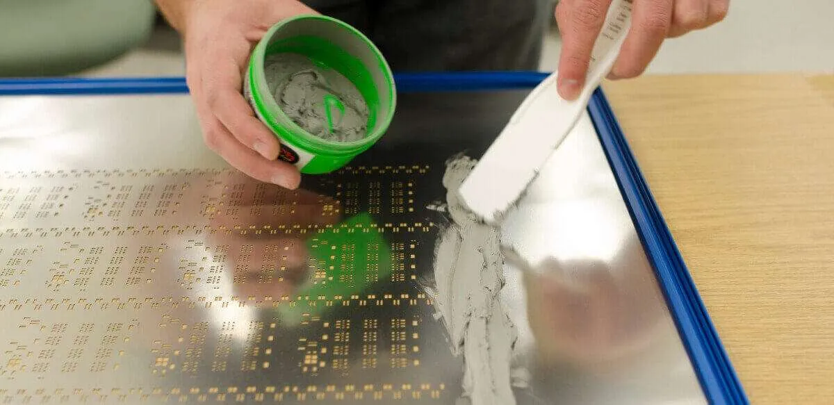 图片放置：在此处插入图像，显示焊膏涂在带有模板的 PCB 上的特写。ALT 文本：“使用 SPI 工艺模板在 PCB 上应用焊膏。